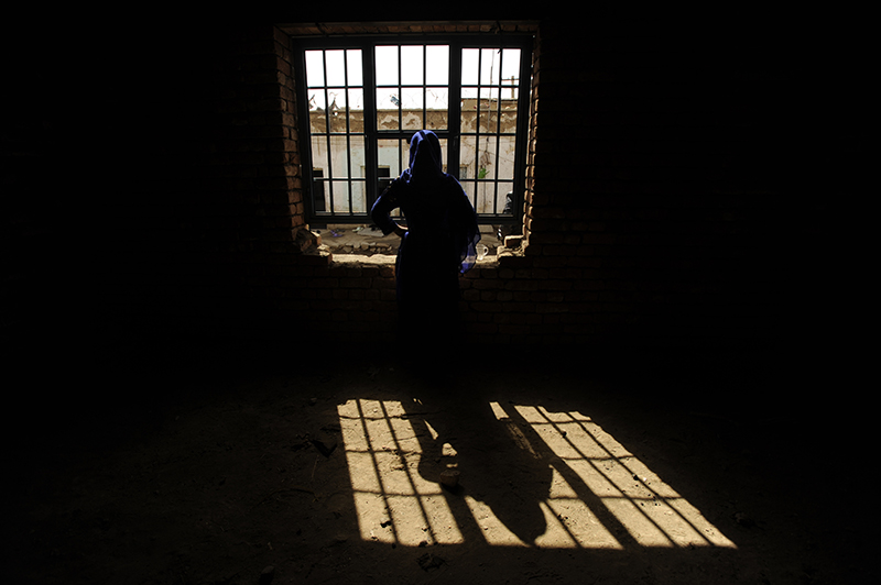 An Afghan women who has been convicted of adultery looks through a window in Parwan prison in a northern province of Kabul. According to this women who doesn’t want to give her name, she was raped by a man in her neighbor and has gave a birth to a child in the prison after Parwan, Afghanistan, 2010. © Farzana Wahidy
