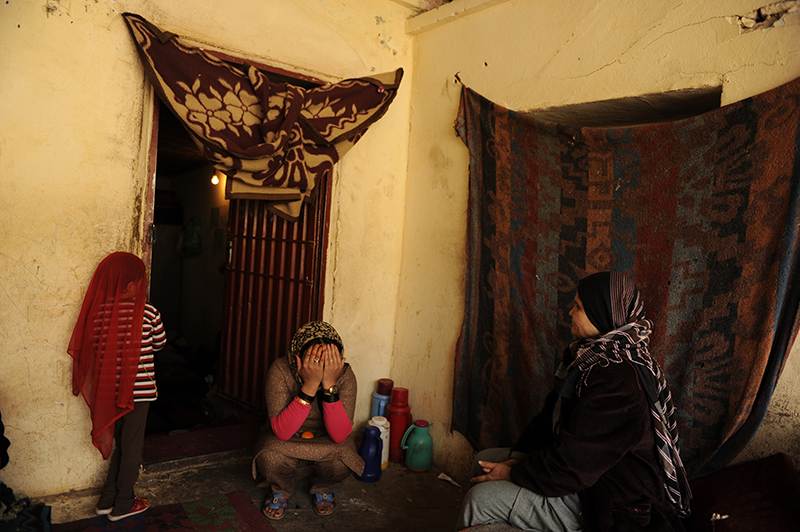 An Afghan female prisoner, meddle, covers her face to be safe in the photo while sitting outside of a room that she share with about other 15 female prisoners,  sits near a prison guard, right, and a child of other prisoner in Mazar-i-Shrif prison in north of Afghanistan, 2010.© Farzana Wahidy